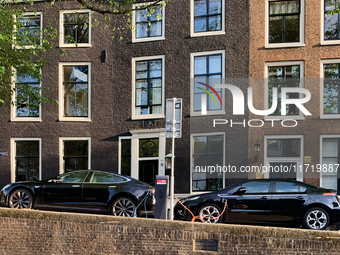 Two electric cars charge at a station located along a canal in central Amsterdam, Netherlands, on July 8, 2019. (