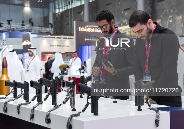 Visitors inspect pistols on display at the 15th edition of the Milipol Qatar 2024 Exhibition and Conference in Doha, Qatar, on October 29, 2...