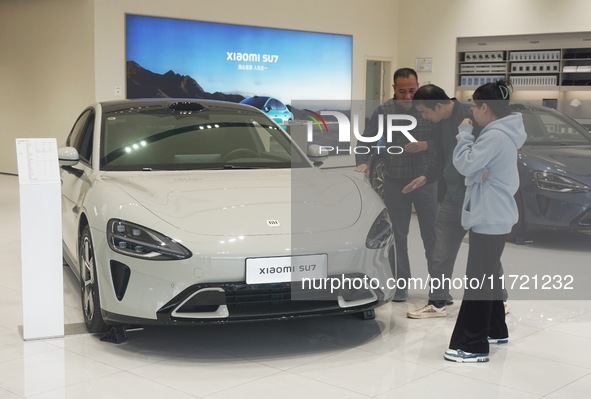 Customers buy a Xiaomi SU7 new energy vehicle at a Xiaomi Auto store in Hangzhou, China, on October 30, 2024. 