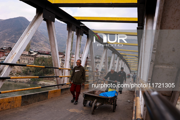 People walk on a cold morning over a bridge in Baramulla, Jammu and Kashmir, India, on October 29, 2024. 