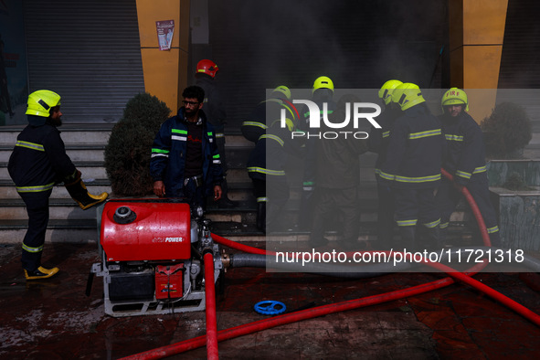 Firefighters try to douse the flames after a fire incident is reported in a commercial building in Srinagar, Jammu and Kashmir, India, on Oc...