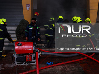 Firefighters try to douse the flames after a fire incident is reported in a commercial building in Srinagar, Jammu and Kashmir, India, on Oc...