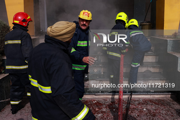 Firefighters try to douse the flames after a fire incident is reported in a commercial building in Srinagar, Jammu and Kashmir, India, on Oc...