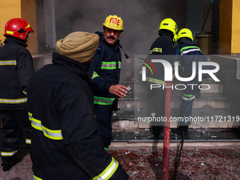 Firefighters try to douse the flames after a fire incident is reported in a commercial building in Srinagar, Jammu and Kashmir, India, on Oc...