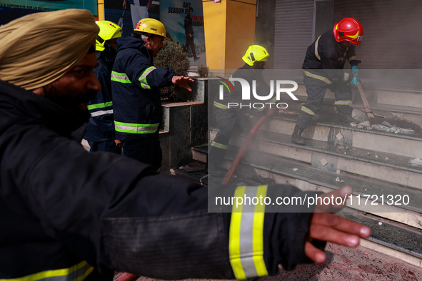 Firefighters try to douse the flames after a fire incident is reported in a commercial building in Srinagar, Jammu and Kashmir, India, on Oc...