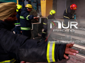 Firefighters try to douse the flames after a fire incident is reported in a commercial building in Srinagar, Jammu and Kashmir, India, on Oc...