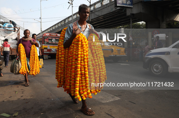 A laborer carries garlands of marigold flowers to supply at a wholesale flower market, which are used to decorate temples and homes, ahead o...