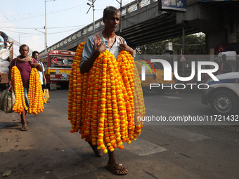 A laborer carries garlands of marigold flowers to supply at a wholesale flower market, which are used to decorate temples and homes, ahead o...