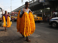 A laborer carries garlands of marigold flowers to supply at a wholesale flower market, which are used to decorate temples and homes, ahead o...