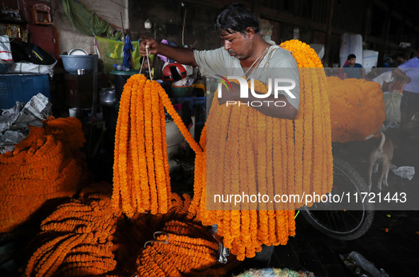 A laborer unloads garlands of marigold flowers at a wholesale flower market, which are used to decorate temples and homes, ahead of the Diwa...