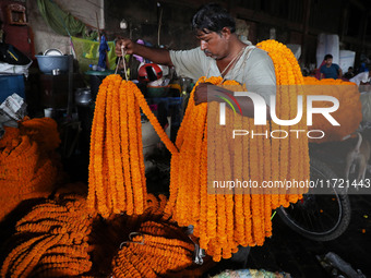 A laborer unloads garlands of marigold flowers at a wholesale flower market, which are used to decorate temples and homes, ahead of the Diwa...