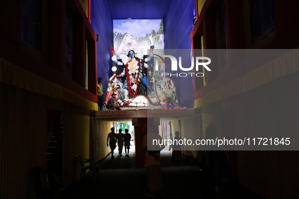 People walk under a ''pandal'' (a temporary platform), a decorated structure, under a huge clay idol of the Hindu goddess Kali, ahead of the...