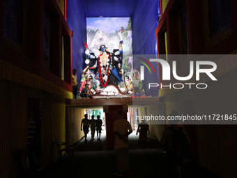 People walk under a ''pandal'' (a temporary platform), a decorated structure, under a huge clay idol of the Hindu goddess Kali, ahead of the...