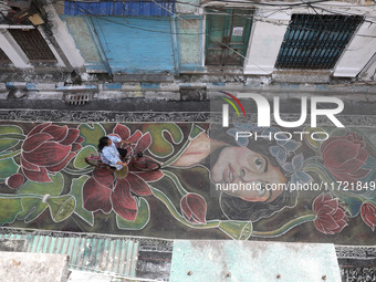 A woman rides a bicycle on the graffiti-painted road in front of a ''pandal,'' a decorated temporary platform, ahead of the Kali Puja festiv...