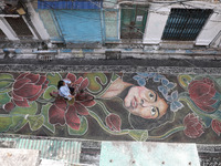 A woman rides a bicycle on the graffiti-painted road in front of a ''pandal,'' a decorated temporary platform, ahead of the Kali Puja festiv...