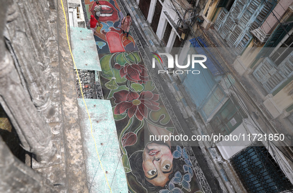 People walk on the graffiti-painted road in front of a ''pandal'' (a temporary platform), a decorated structure, ahead of the Kali Puja fest...