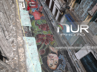 People walk on the graffiti-painted road in front of a ''pandal'' (a temporary platform), a decorated structure, ahead of the Kali Puja fest...