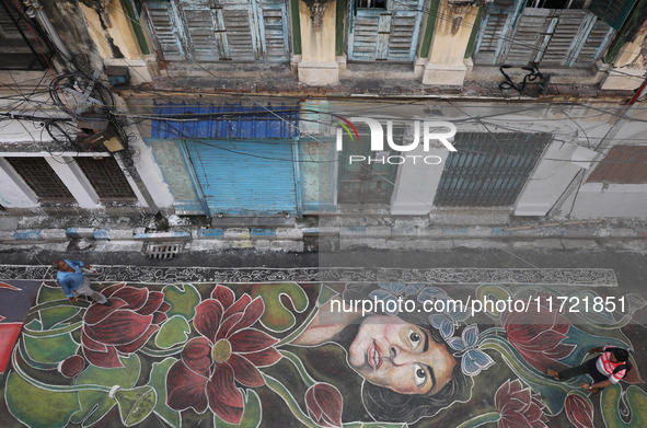 People walk on the graffiti-painted road in front of a ''pandal'' (a temporary platform), a decorated structure, ahead of the Kali Puja fest...