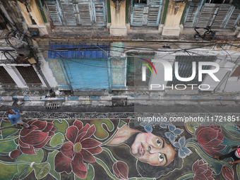 People walk on the graffiti-painted road in front of a ''pandal'' (a temporary platform), a decorated structure, ahead of the Kali Puja fest...