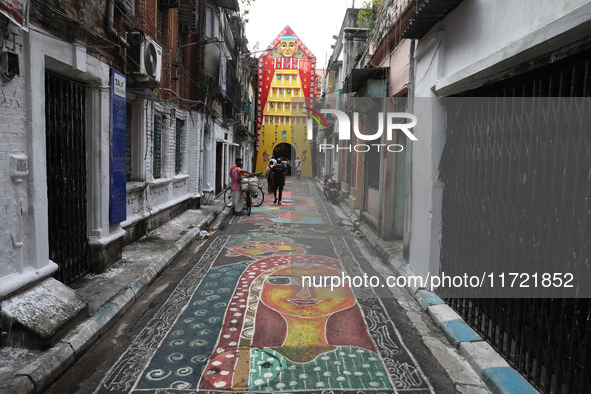 People walk on the graffiti-painted road in front of a ''pandal'' (a temporary platform), a decorated structure, ahead of the Kali Puja fest...