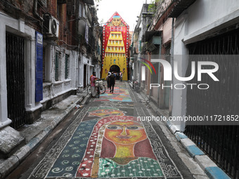 People walk on the graffiti-painted road in front of a ''pandal'' (a temporary platform), a decorated structure, ahead of the Kali Puja fest...