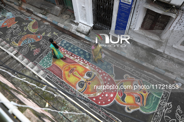 People walk on the graffiti-painted road in front of a ''pandal'' (a temporary platform), a decorated structure, ahead of the Kali Puja fest...