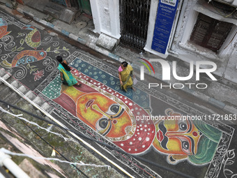 People walk on the graffiti-painted road in front of a ''pandal'' (a temporary platform), a decorated structure, ahead of the Kali Puja fest...