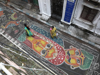 People walk on the graffiti-painted road in front of a ''pandal'' (a temporary platform), a decorated structure, ahead of the Kali Puja fest...