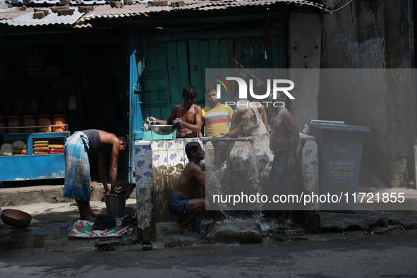 Men bathe at a roadside municipal tap outside a ''pandal'' (a temporary platform), a decorated structure, ahead of the Kali Puja festival in...