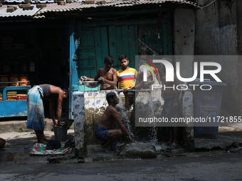 Men bathe at a roadside municipal tap outside a ''pandal'' (a temporary platform), a decorated structure, ahead of the Kali Puja festival in...