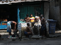 Men bathe at a roadside municipal tap outside a ''pandal'' (a temporary platform), a decorated structure, ahead of the Kali Puja festival in...