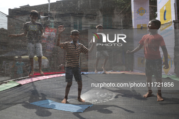 Children jump on a trampoline at a fair outside a ''pandal,'' a decorated temporary platform, ahead of the Kali Puja festival in Kolkata, In...