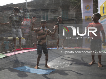 Children jump on a trampoline at a fair outside a ''pandal,'' a decorated temporary platform, ahead of the Kali Puja festival in Kolkata, In...