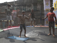 Children jump on a trampoline at a fair outside a ''pandal,'' a decorated temporary platform, ahead of the Kali Puja festival in Kolkata, In...