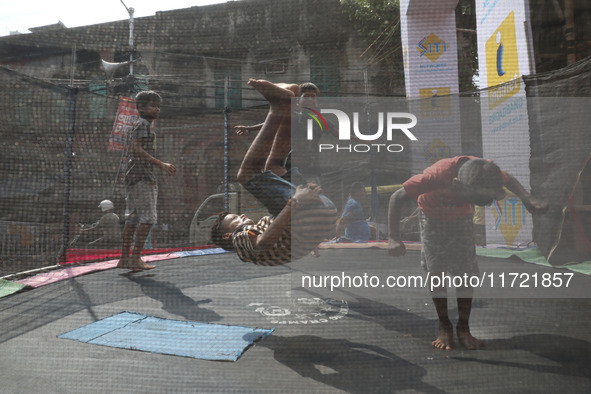 Children jump on a trampoline at a fair outside a ''pandal,'' a decorated temporary platform, ahead of the Kali Puja festival in Kolkata, In...