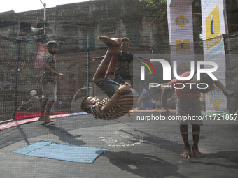 Children jump on a trampoline at a fair outside a ''pandal,'' a decorated temporary platform, ahead of the Kali Puja festival in Kolkata, In...