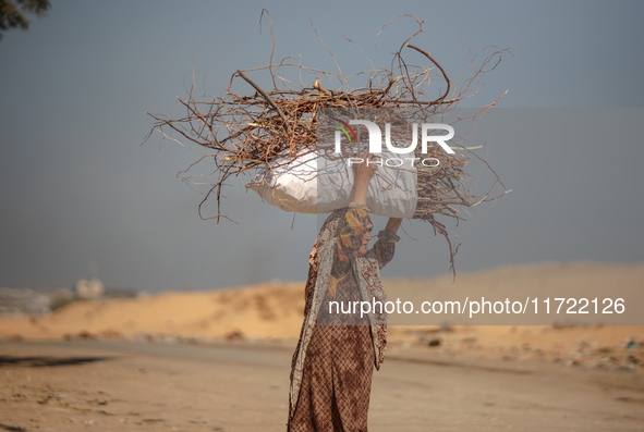 A woman carries firewood and walks along a street in Khan Yunis, Gaza Strip, on October 30, 2024, amid the ongoing conflict between Israel a...