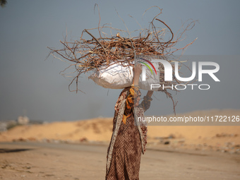 A woman carries firewood and walks along a street in Khan Yunis, Gaza Strip, on October 30, 2024, amid the ongoing conflict between Israel a...