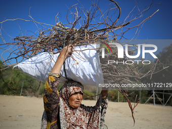 A woman carries firewood and walks along a street in Khan Yunis, Gaza Strip, on October 30, 2024, amid the ongoing conflict between Israel a...