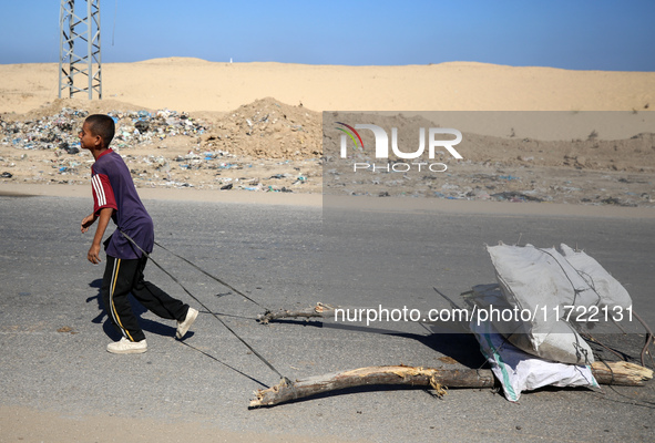 A Palestinian boy pulls sacks loaded with salvaged firewood and walks along a street in Khan Yunis, southern Gaza Strip, on October 30, 2024...