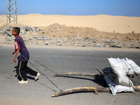 A Palestinian boy pulls sacks loaded with salvaged firewood and walks along a street in Khan Yunis, southern Gaza Strip, on October 30, 2024...