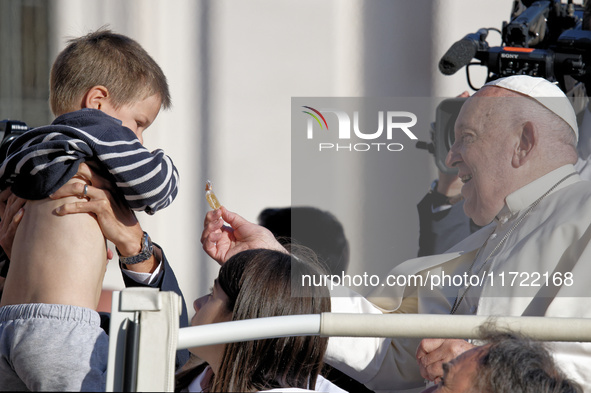 Pope Francis greets a baby as he arrives for the weekly general audience at Saint Peter's Square in The Vatican on October 30, 2024. 