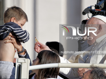 Pope Francis greets a baby as he arrives for the weekly general audience at Saint Peter's Square in The Vatican on October 30, 2024. (