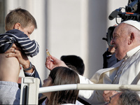 Pope Francis greets a baby as he arrives for the weekly general audience at Saint Peter's Square in The Vatican on October 30, 2024. (