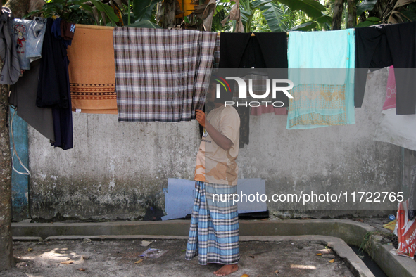 A Rohingya refugee checks clothes that dry in the sun at a temporary shelter for Rohingya refugees at the Pantai Labu District Office in Del...