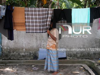 A Rohingya refugee checks clothes that dry in the sun at a temporary shelter for Rohingya refugees at the Pantai Labu District Office in Del...