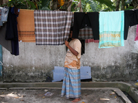 A Rohingya refugee checks clothes that dry in the sun at a temporary shelter for Rohingya refugees at the Pantai Labu District Office in Del...