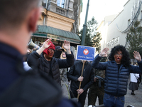 Participants of the counter-demonstration organized by the All-Polish Youth dress as refugees in blackface, and Polish soldiers point rifles...