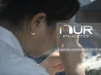 An employee processes medical endoscope lenses at the production workshop of Hangzhou HAoke Optoelectronic Instrument Co., LTD., located in...