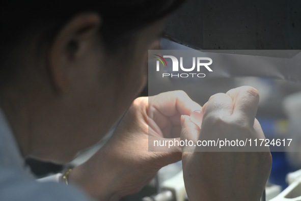 An employee processes medical endoscope lenses at the production workshop of Hangzhou HAoke Optoelectronic Instrument Co., LTD., located in...